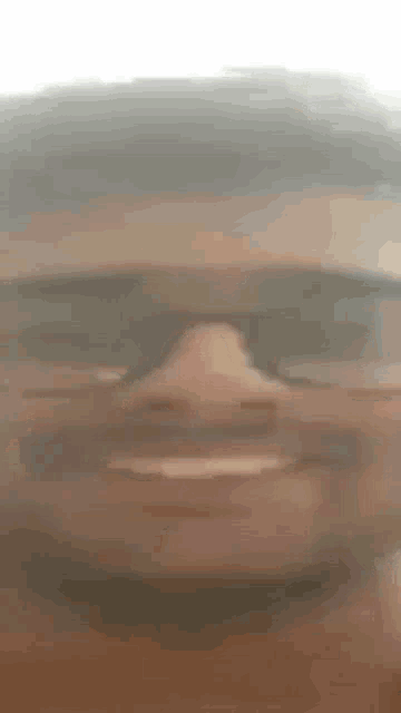 a close up of a man 's face wearing sunglasses and smiling .