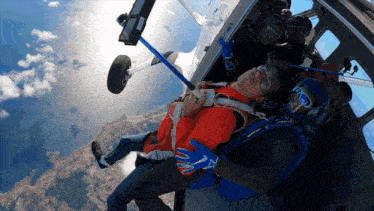 a man in a red jacket is laying on the ground in the air