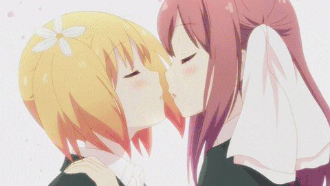 a girl with a flower in her hair kisses another girl on the cheek