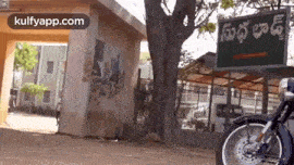 a motorcycle is parked in front of a building with a green sign that says ' a ' on it .