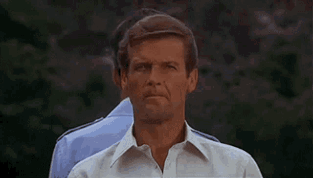a man in a white shirt is standing next to another man in a blue shirt and looking at the camera .