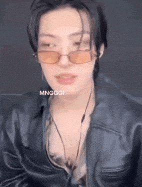 a young man wearing sunglasses and a leather jacket is talking .