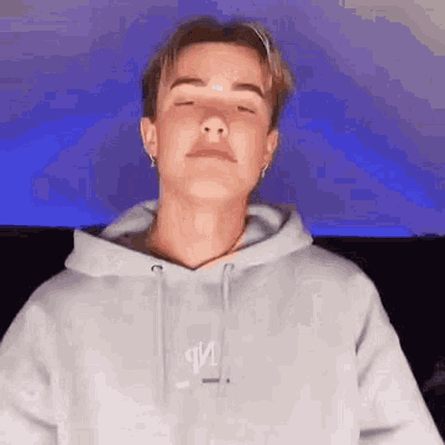 a young man in a grey hoodie is making a funny face .