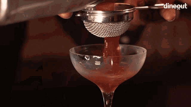 a person is holding a martini glass with foam coming out of it and the word dinegut is on the bottom