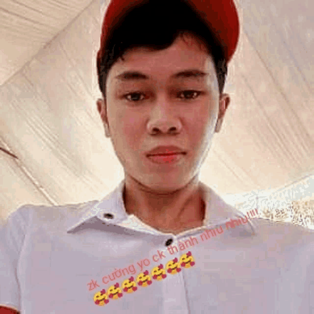 a young man wearing a red hat and a white shirt is taking a selfie .
