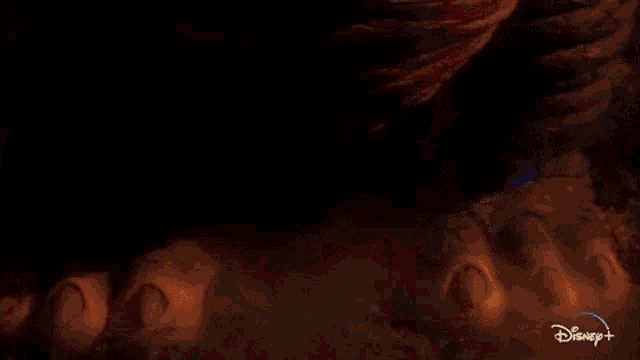a close up of a dinosaur 's face with a disney + logo in the corner .