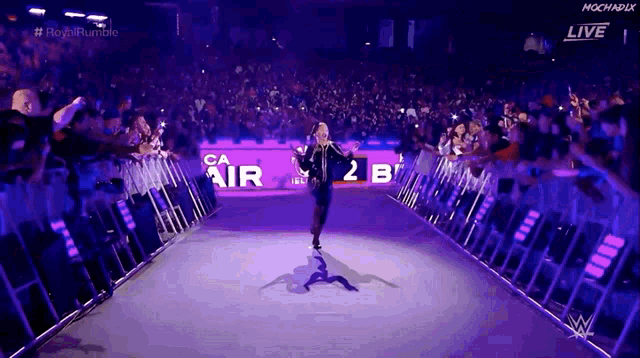 a wrestler walks down a purple aisle with a sign that says ca air 2b