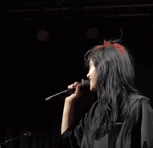 a woman with red hair is wearing a black dress and holding a microphone .
