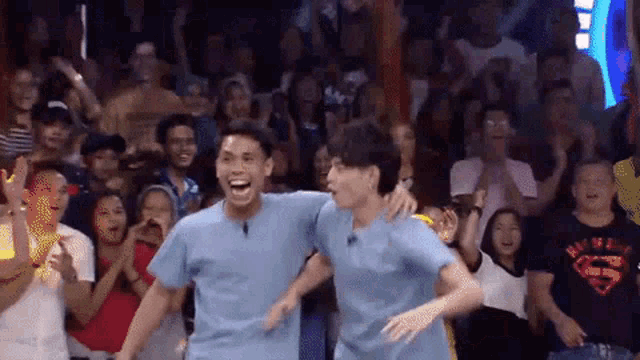 two men are dancing in front of a crowd with one wearing a superman t-shirt
