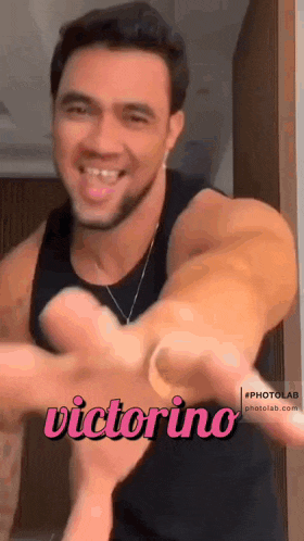 a man in a black tank top is smiling and giving a thumbs up with the name victorino above him .