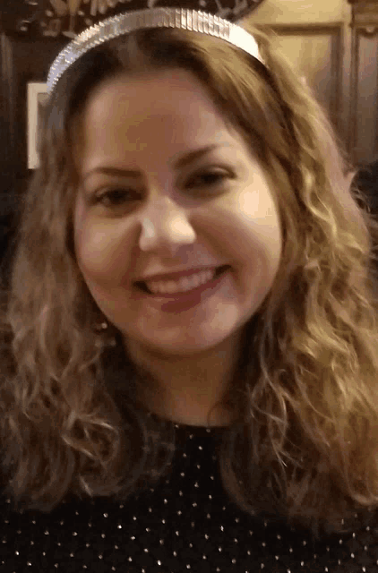 a woman wearing a silver headband is smiling