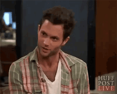 a man wearing a plaid shirt and a white shirt is sitting in front of a television .