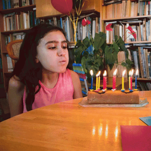 a little girl blowing out candles on a birthday cake