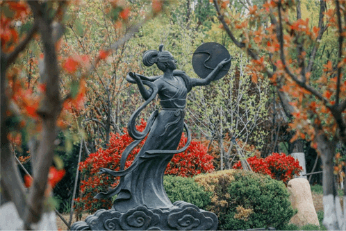 a statue of a woman is surrounded by trees and bushes
