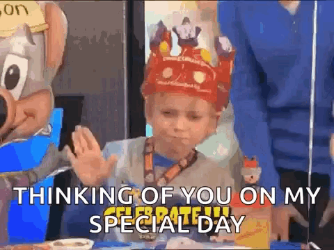 a young boy wearing a crown is sitting at a table with a chipotle mascot .