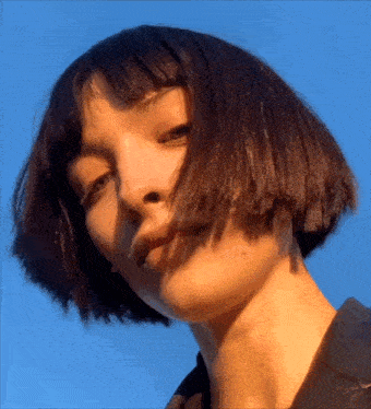 a close up of a woman 's face with blue sky in the background