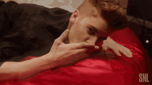 a man laying on a bed with the snl logo on the bottom
