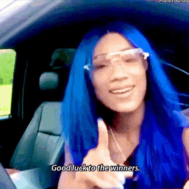 a woman with blue hair and glasses is giving a thumbs up and says good luck to the winners