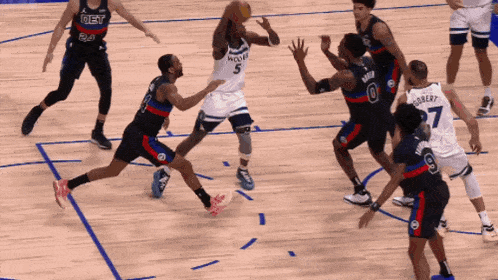 a basketball player with the number 5 on his jersey tries to get the ball