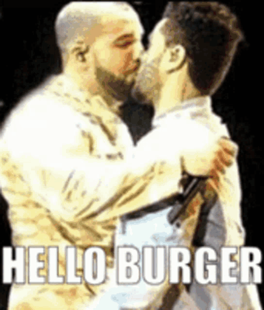 a man is kissing another man on the cheek while holding a microphone with the words `` hello burger '' written on it .