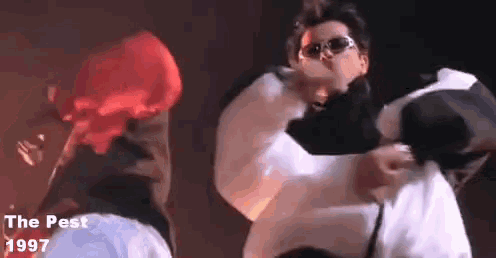 a man wearing sunglasses is holding another man in his arms in a video from the movie the pest .