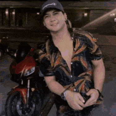 a man wearing a hat is standing next to a motorcycle and smiling .