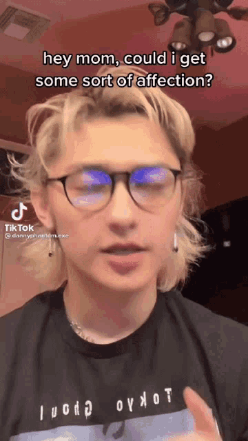 a young man wearing glasses and a black shirt with the words hey mom could i get some sort of affection on it