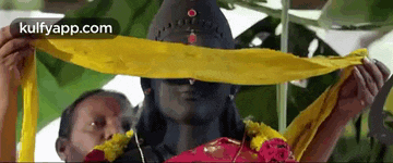 a man is holding a yellow cloth over a statue .