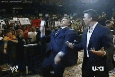 a man in a suit is dancing in front of a crowd while a man in a suit talks to him ..