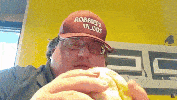 a man wearing a red hat that says robbie 's vlogs