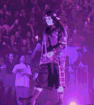 a man in a kilt is standing on a stage with a microphone in front of a crowd .
