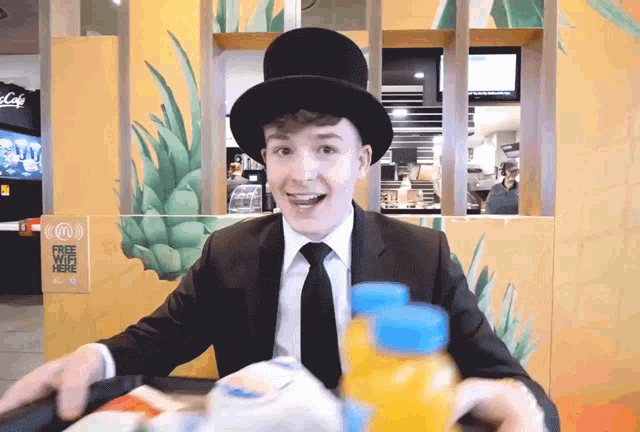 a man in a top hat sits at a table in front of a sign that says free wifi