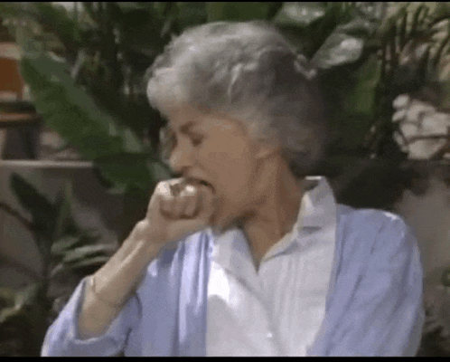 an elderly woman in a blue cardigan is biting her nails .
