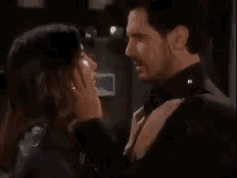 a man and a woman are kissing in front of a black background .
