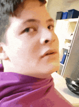 a close up of a person 's face with a purple sweatshirt on