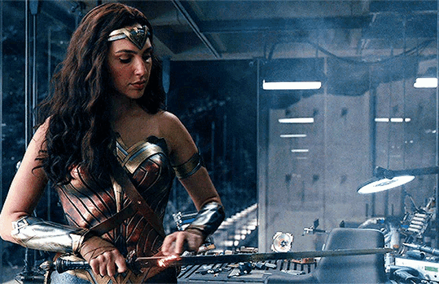 wonder woman is holding a sword in a dark room