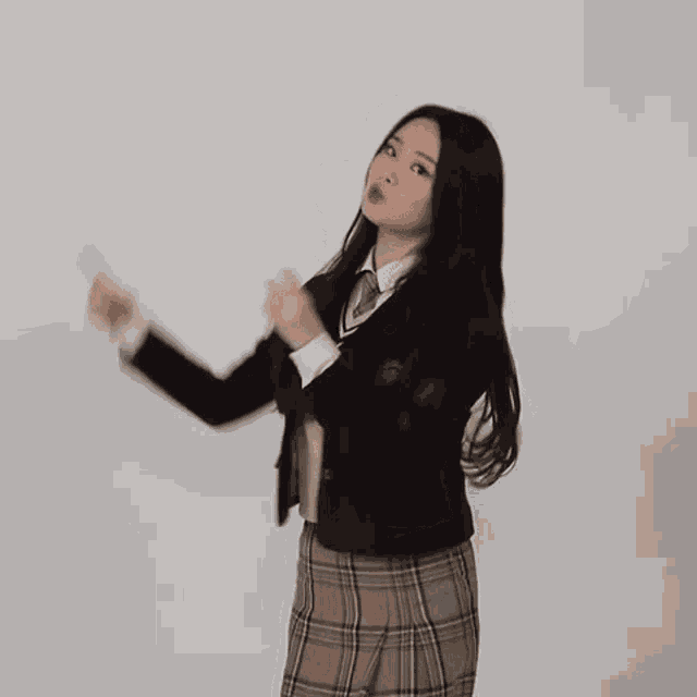 a young woman in a school uniform is dancing and smiling .