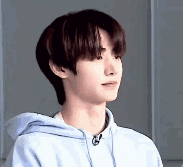 a close up of a young man wearing a blue hoodie and looking at the camera .