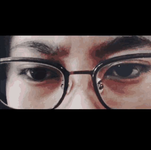 a close up of a person wearing glasses with a tear coming out of their eye