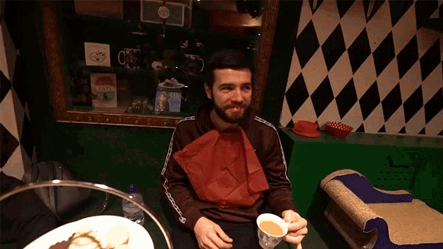 a man sitting at a table with a cup of tea in front of him