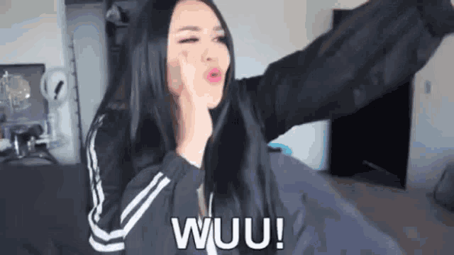 a woman with long black hair is making a funny face while holding her hand to her face .
