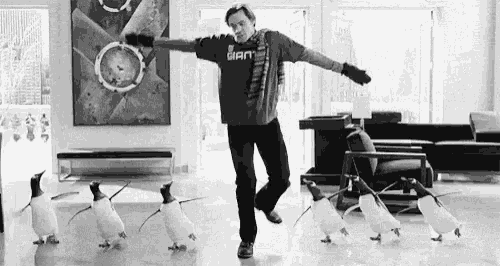 a black and white photo of a man dancing with penguins .