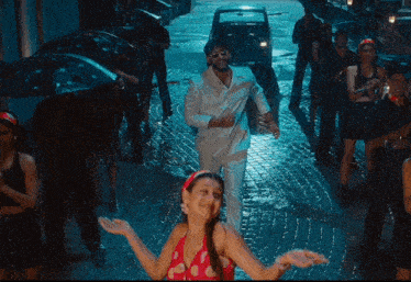 a man in a white suit is holding a woman in a red polka dot top in the rain