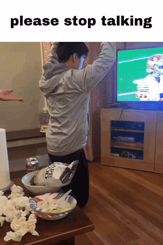 a man is kneeling down in front of a television with the words please stop talking above him