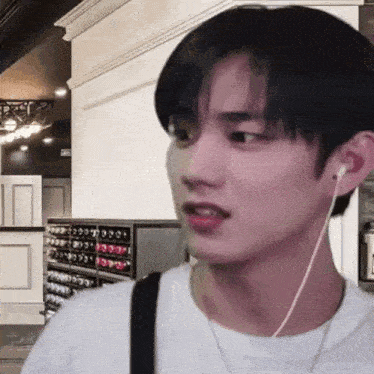 a young man wearing headphones and a white shirt is looking at the camera .
