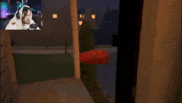 a man wearing headphones is playing a video game with a red object in the background