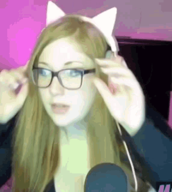 a woman wearing glasses and a cat ear headband looks at the camera