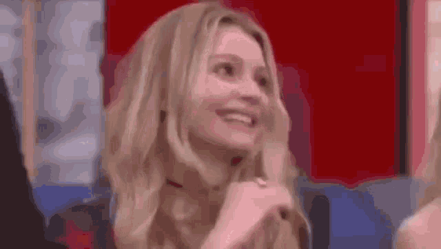 a woman is smiling and laughing in front of a red wall .