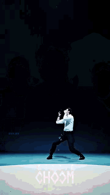 a man in a white shirt and black pants is kneeling down in front of a sign that says hoom