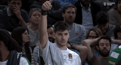 a man in a magenta sport shirt holds up his hand in the air